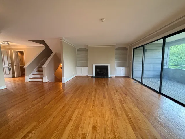 a view of empty room with wooden floor and fireplace