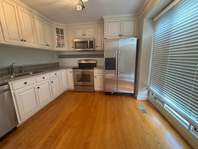 a kitchen with granite countertop a refrigerator and a stove top oven