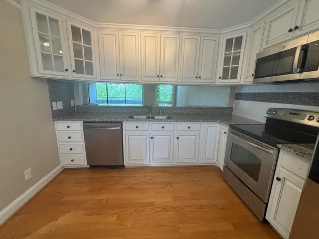 a kitchen with stainless steel appliances granite countertop a stove a sink and a microwave
