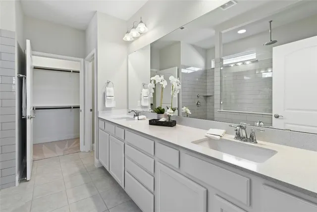 a bathroom with a double vanity sink mirror and shower
