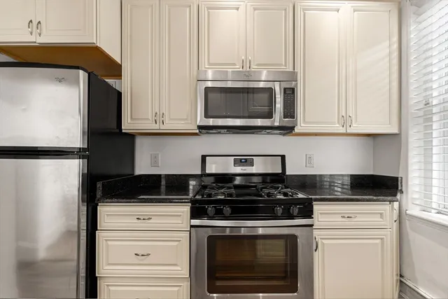a kitchen with stainless steel appliances granite countertop white cabinets and a stove a refrigerator with white cabinets