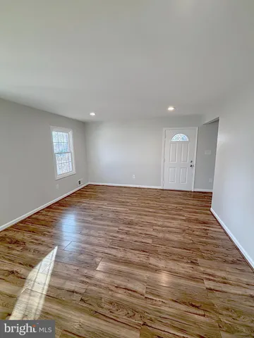 a view of empty room with wooden floor and window