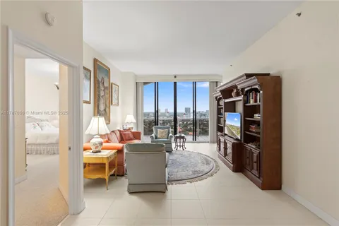 a living room with furniture a flat screen tv and floor to ceiling window