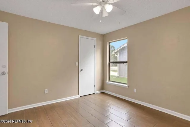 an empty room with chandelier fan and windows