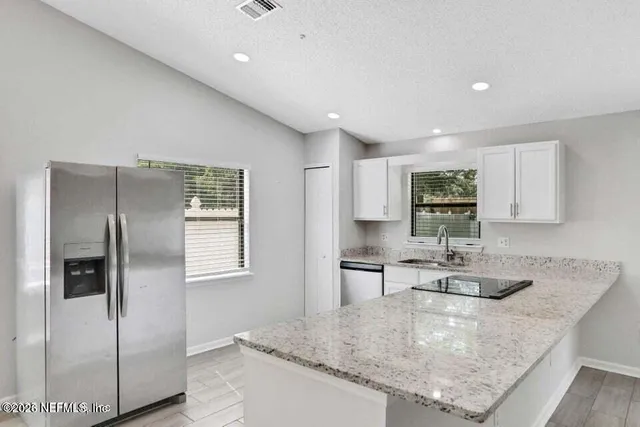 a kitchen with stainless steel appliances granite countertop a sink a refrigerator and a granite counter tops