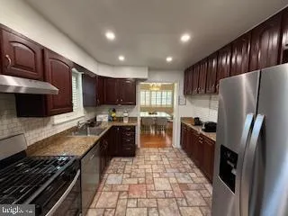 a large kitchen with kitchen island granite countertop a stove refrigerator and cabinets