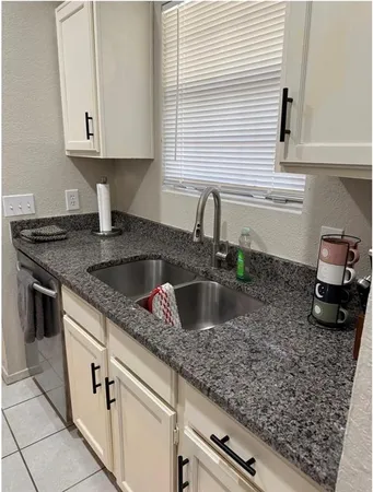 a kitchen with granite countertop a sink a stove and cabinets