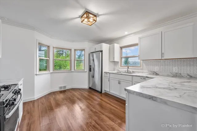 a kitchen with a refrigerator a stove a microwave and a window