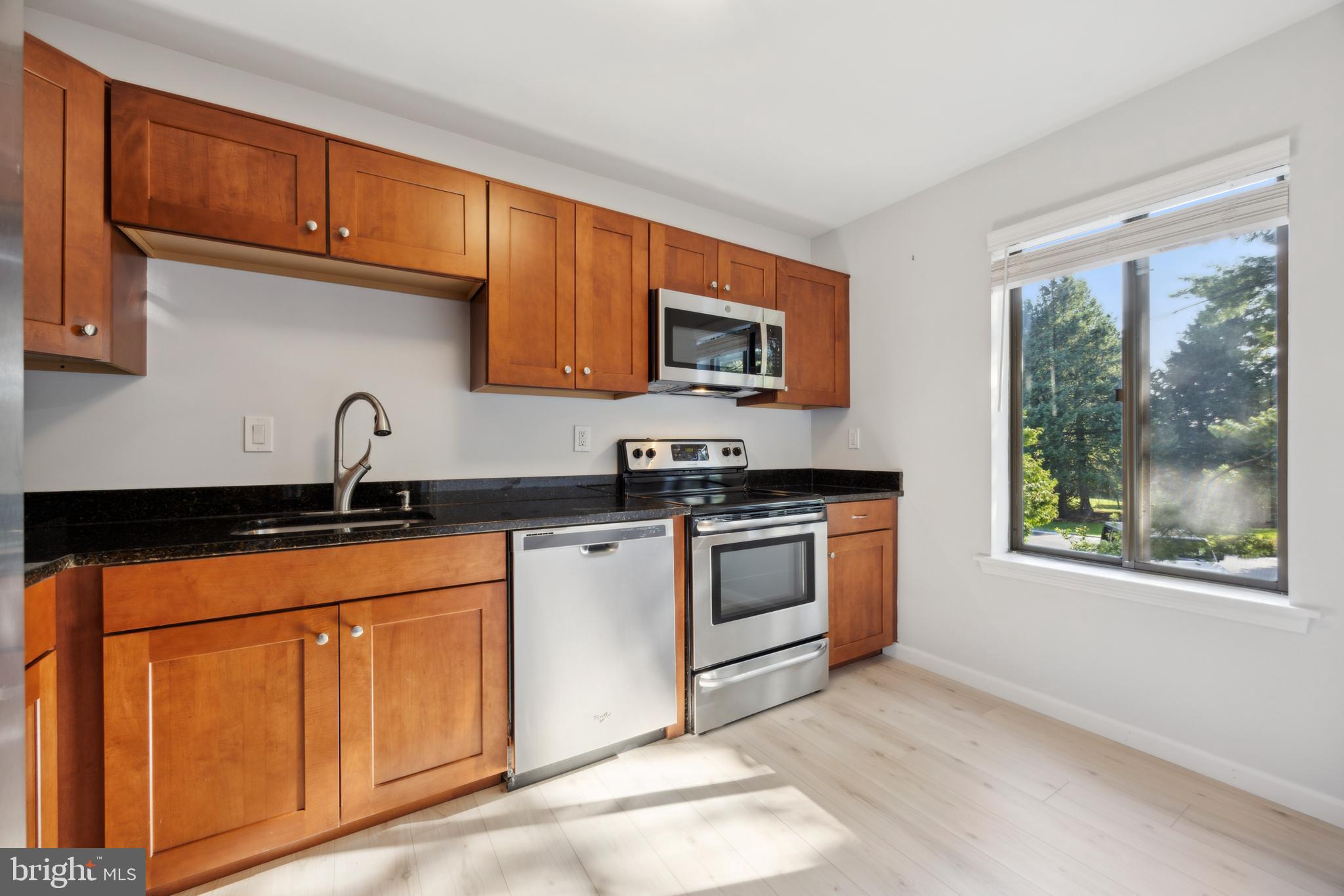 411 Conestoga Road, Unit 27 Devon, PA 19333 - Photo 3 of 15 a kitchen with granite countertop a sink cabinets stainless steel appliances and a window