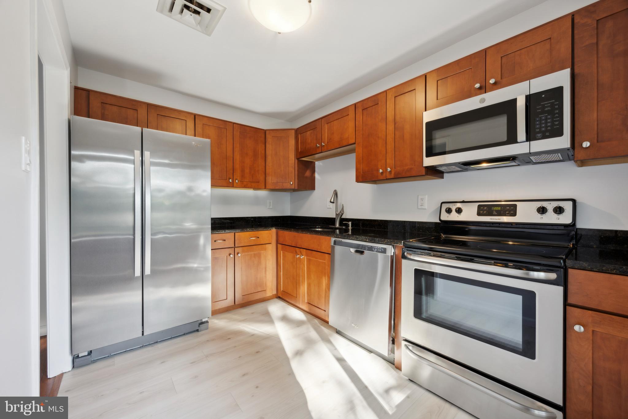 411 Conestoga Road, Unit 27 Devon, PA 19333 - Photo 4 of 15 a kitchen with stainless steel appliances granite countertop a stove a microwave and a refrigerator