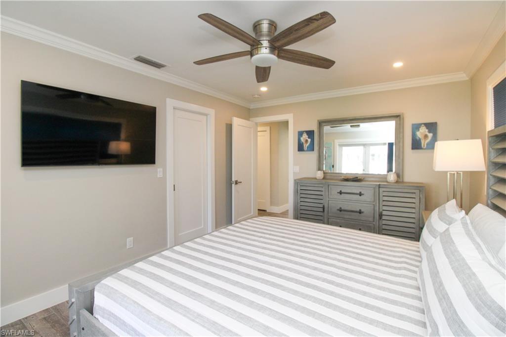 1353 Pelican Avenue Naples, FL 34102 - Photo 29 of 41 a bedroom with a bed a mirror and a flat screen tv