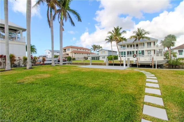 a front view of a building with garden and trees