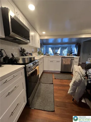 a kitchen with granite countertop a stove top oven a sink dishwasher and a microwave oven with wooden floor