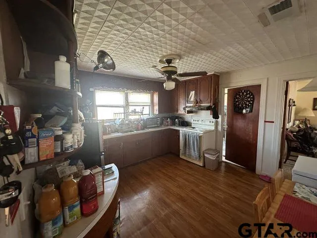 a kitchen with stainless steel appliances granite countertop a refrigerator a sink dishwasher a stove and a dining table with wooden floor