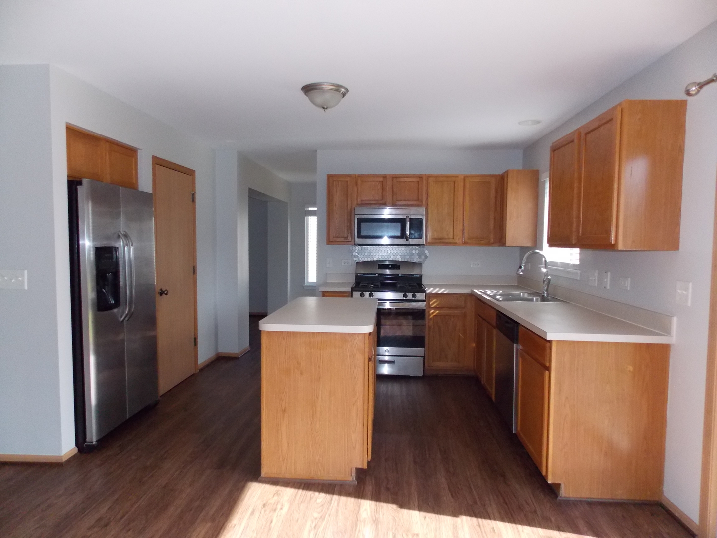 3312 Allen Street Plano, IL 60545 - Photo 9 of 21 a kitchen with stainless steel appliances a refrigerator a stove a sink a center island and wooden floor