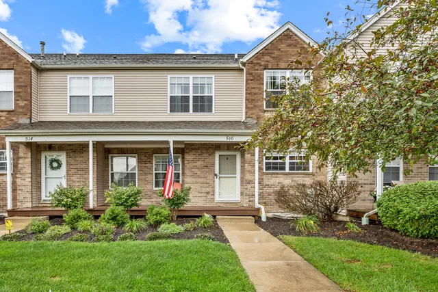 a front view of a house with a yard and potted plants
