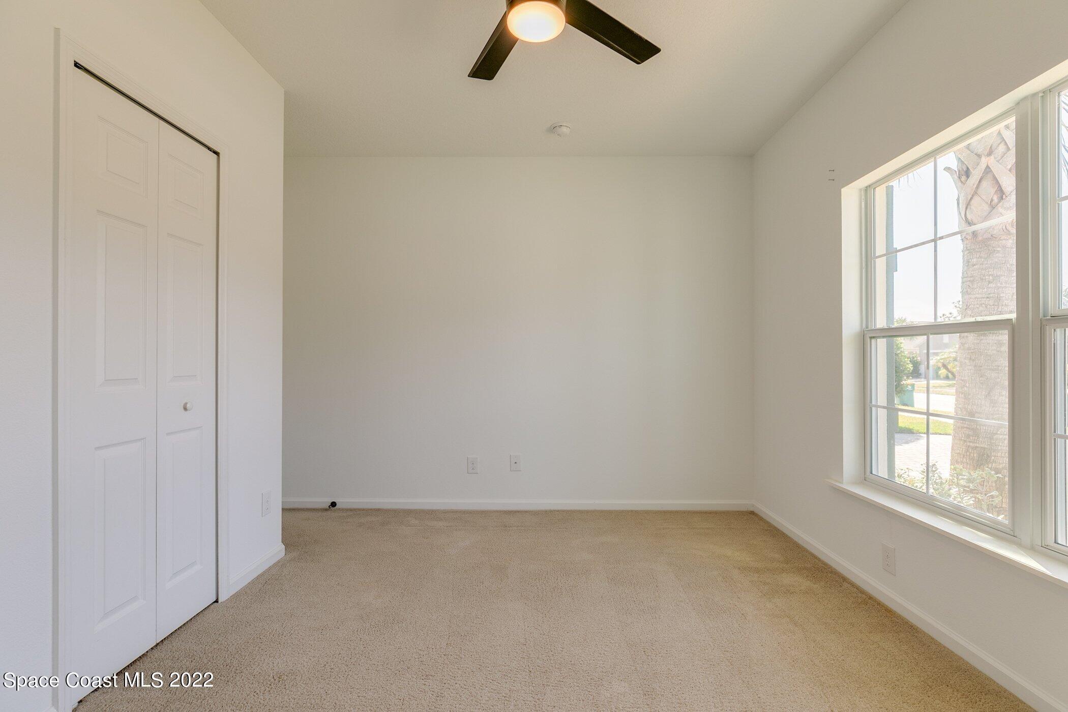 3555 Tabitha Court Melbourne, FL 32934 - Photo 23 of 30 an empty room with chandelier fan and windows