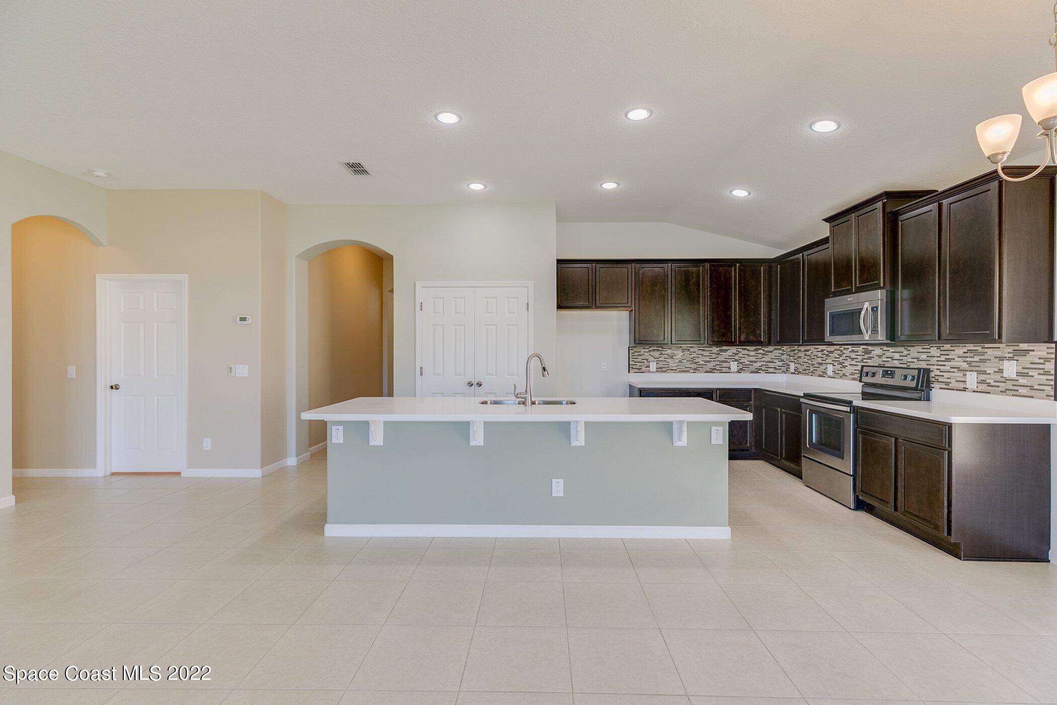 3555 Tabitha Court Melbourne, FL 32934 - Photo 7 of 30 a large kitchen with a large counter top stainless steel appliances and cabinets