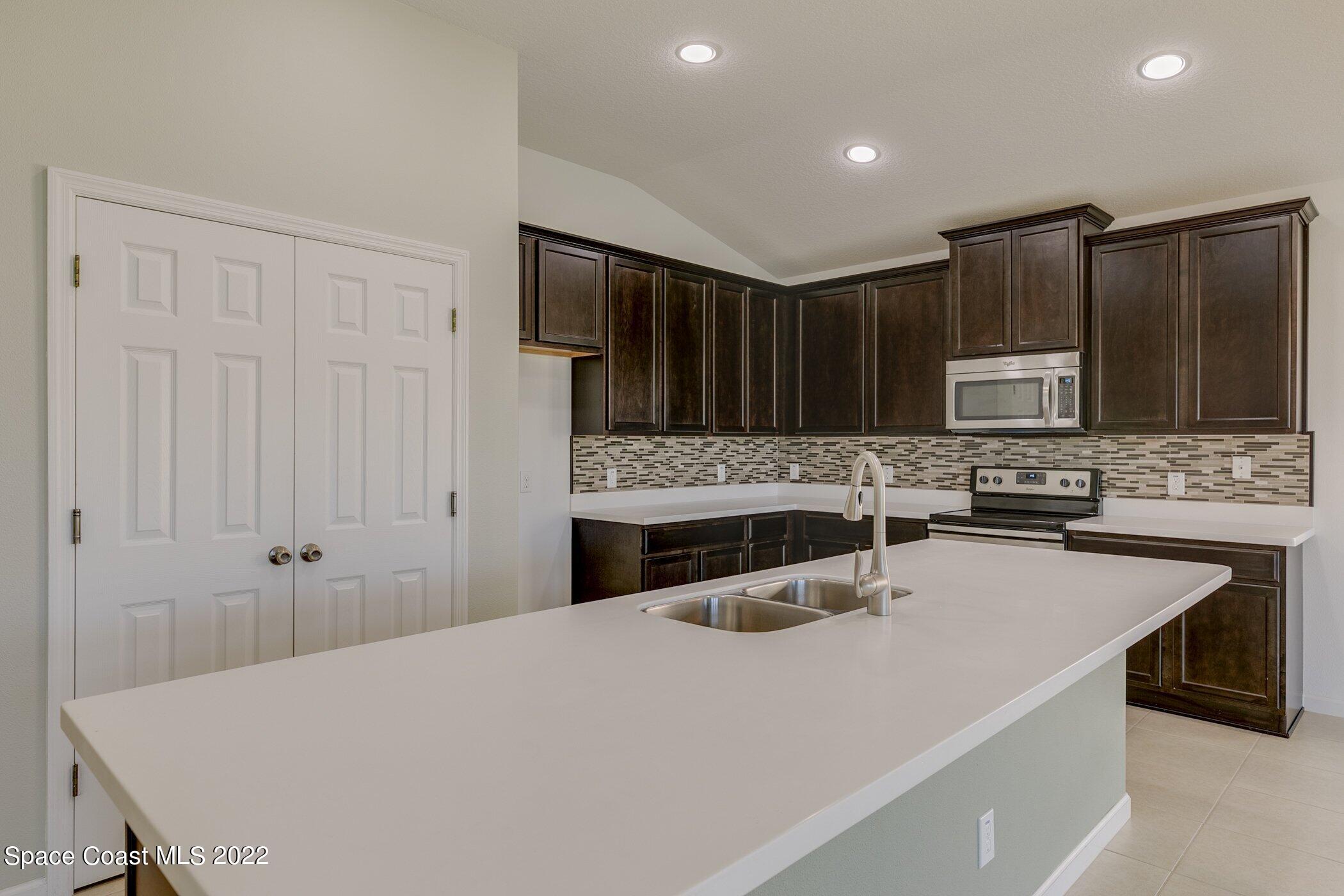 3555 Tabitha Court Melbourne, FL 32934 - Photo 8 of 30 a kitchen with granite countertop a sink stainless steel appliances and cabinets