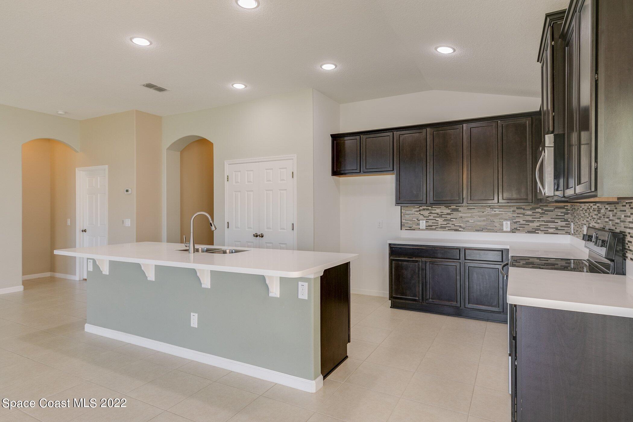 3555 Tabitha Court Melbourne, FL 32934 - Photo 9 of 30 a large kitchen with stainless steel appliances a large counter top a stove a sink and a refrigerator