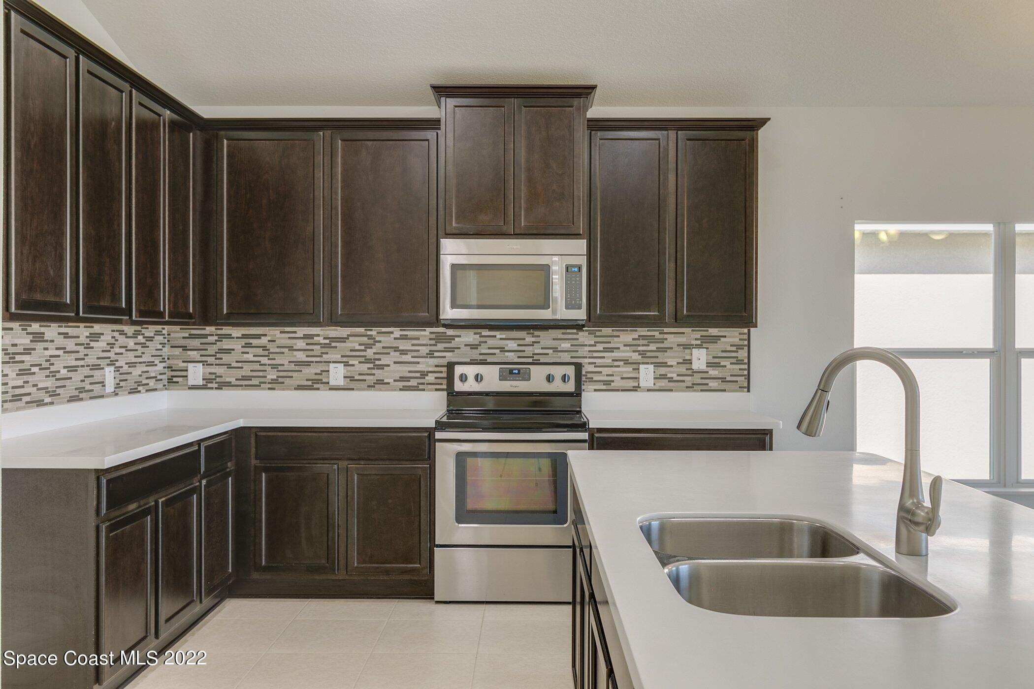 3555 Tabitha Court Melbourne, FL 32934 - Photo 10 of 30 a kitchen with stainless steel appliances granite countertop a sink and a microwave