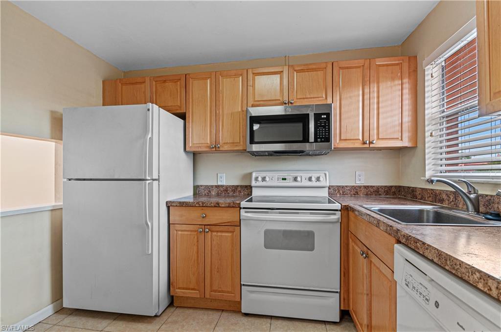 225 Turtle Lake Court, Unit 209 Naples, FL 34105 - Photo 9 of 15 a kitchen with white cabinets sink and stainless steel appliances