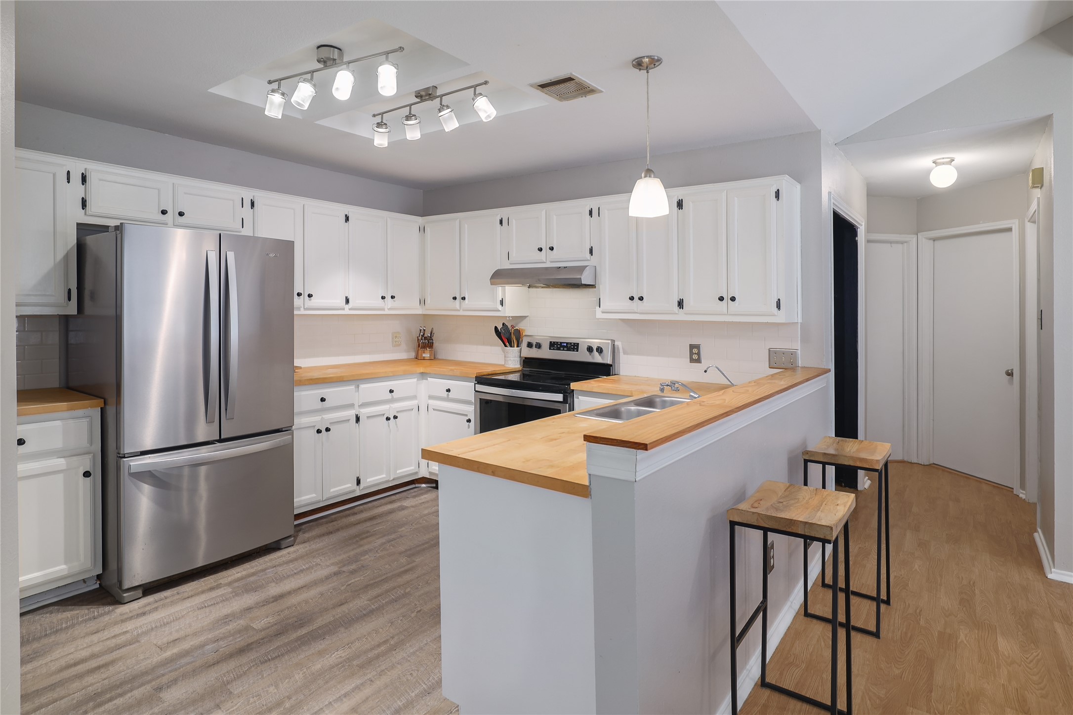 827 Topaz Lane Leander, TX 78641 - Photo 11 of 22 a kitchen with stainless steel appliances granite countertop a refrigerator a sink dishwasher a stove and white cabinets with wooden floor