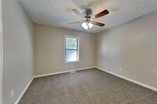 an empty room with windows and chandelier fan