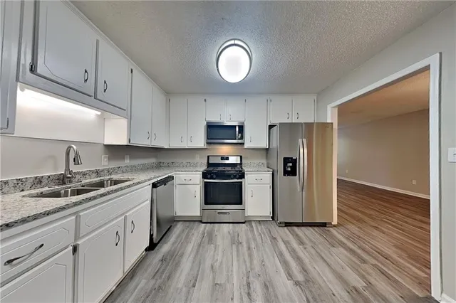 a kitchen with granite countertop a refrigerator stove top oven and sink