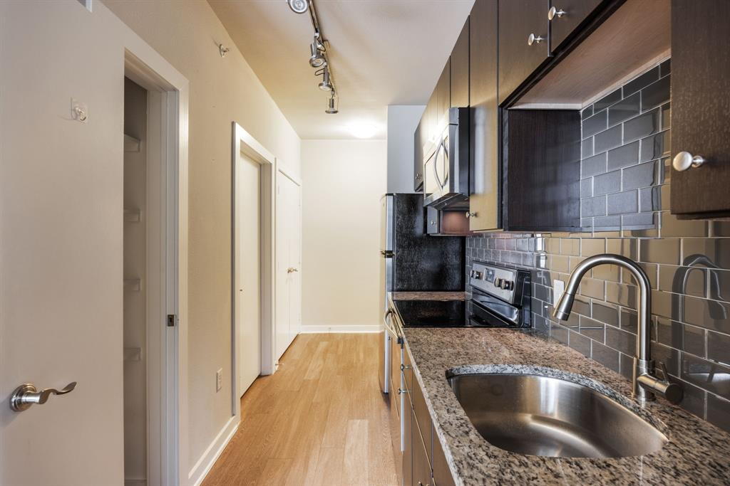 1900 Barton Springs Road, Unit 3013 Austin, TX 78704 - Photo 8 of 27 A compact kitchen boasts granite counters, modern appliances, and sleek dark cabinetry.