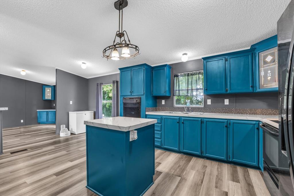 3615 Spring Valley Road Lorena, TX 76655 - Photo 5 of 33 Kitchen featuring blue cabinetry, light-toned wood-finish flooring, a central island with a light countertop, a built-in oven, and a mosaic tile backsplash