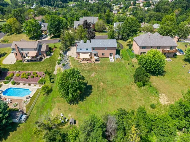 an aerial view of residential houses with outdoor space and trees