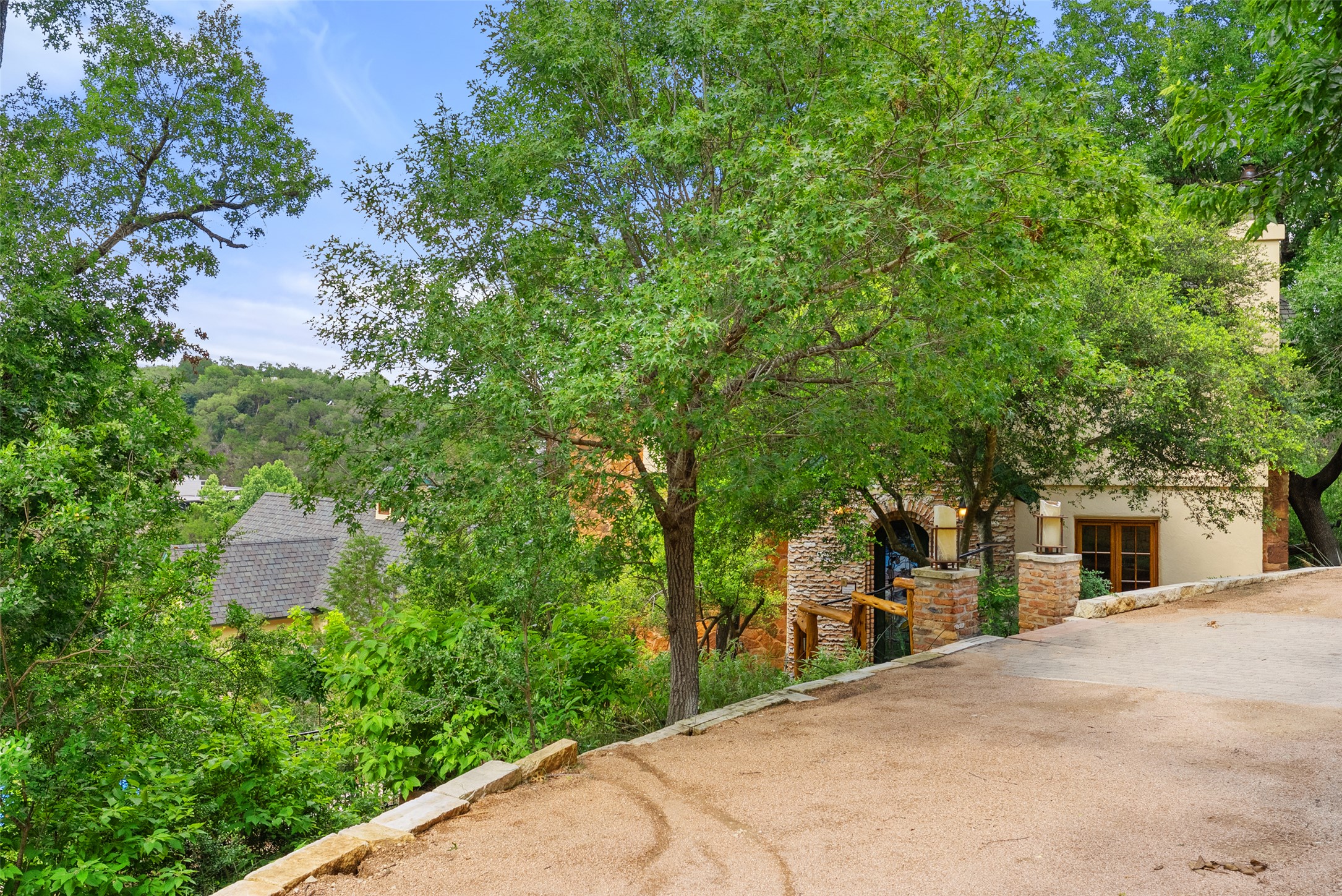 1354 The High Road Austin, TX 78746 - Photo 37 of 40 Hillside home with upper driveway and solar panel carport, nestled among verdant trees offers a serene escape with scenic vistas.