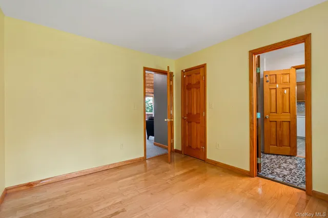 a view of an empty room with a window and wooden floor