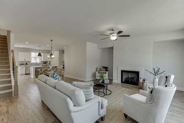 a living room with furniture a fireplace and a ceiling fan