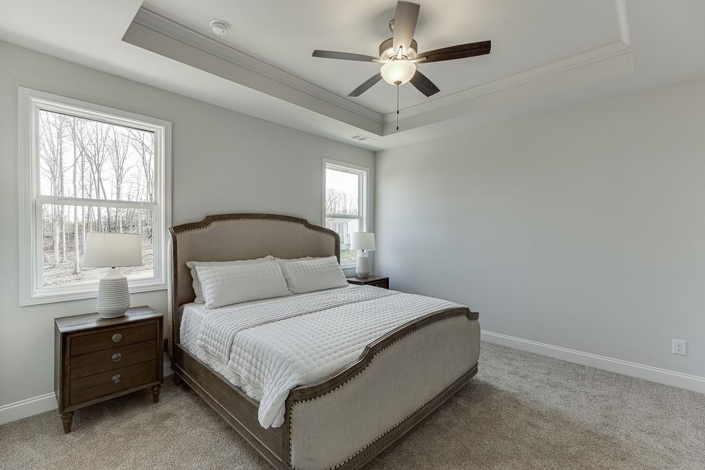 1276 Ainsworth Alley Sugar Hill, GA 30518 - Photo 21 of 56 a bedroom with a large bed and a chandelier