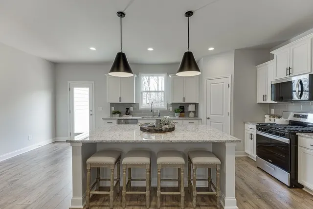 a kitchen with granite countertop a stove a sink a dining table and chairs