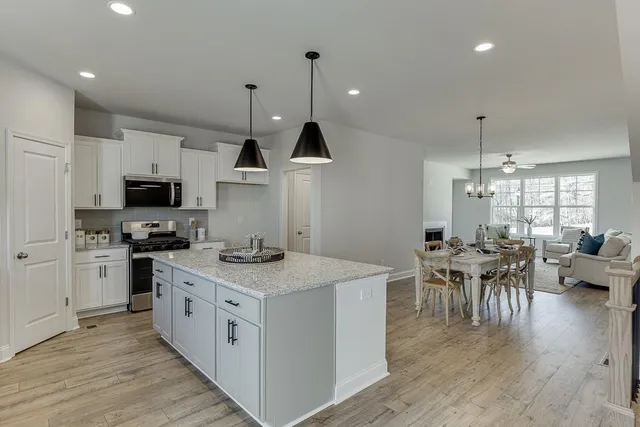 a kitchen with stainless steel appliances granite countertop a stove top oven a sink dishwasher a dining table and chairs with wooden floor