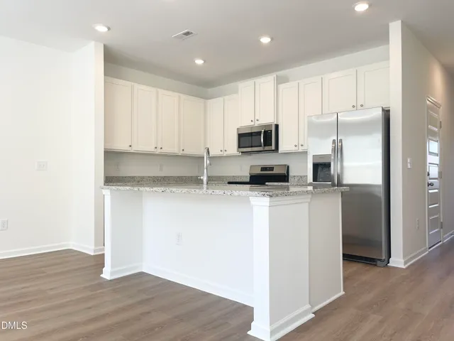a kitchen with kitchen island a refrigerator sink and cabinets