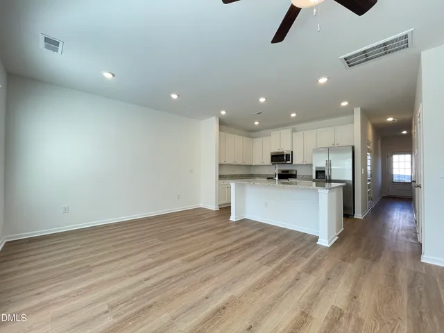 a view of kitchen with kitchen island wooden floors granite counter tops and white cabinets