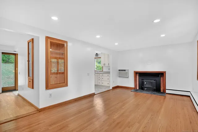 an empty room with wooden floor fireplace and windows