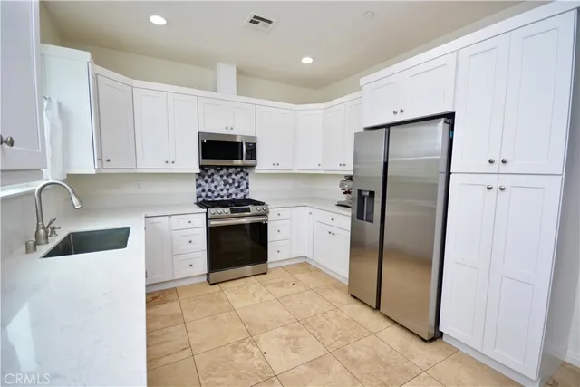 a kitchen with granite countertop a refrigerator sink and cabinets
