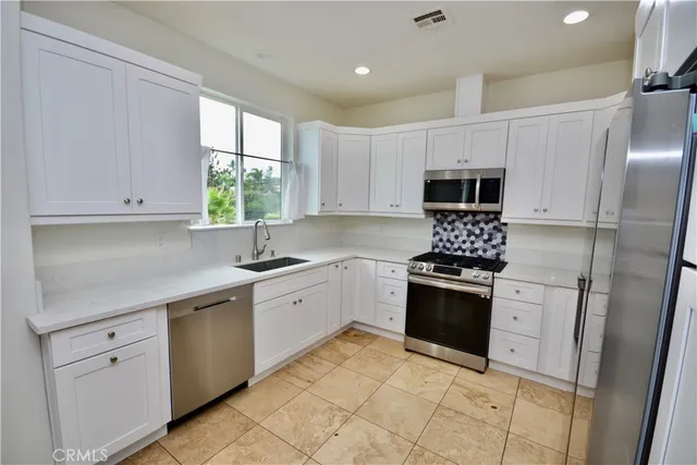 a kitchen with cabinets stainless steel appliances a sink and a window