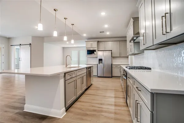 a large kitchen with stainless steel appliances granite countertop a sink a stove and a refrigerator