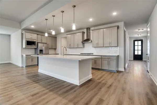 a large white kitchen with kitchen island a sink table and chairs