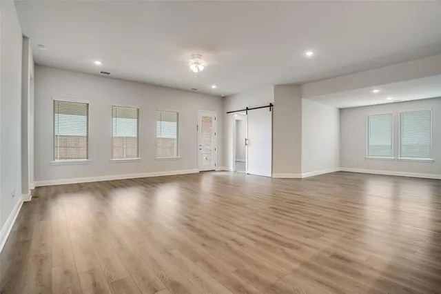a view of empty room with wooden floor and windows