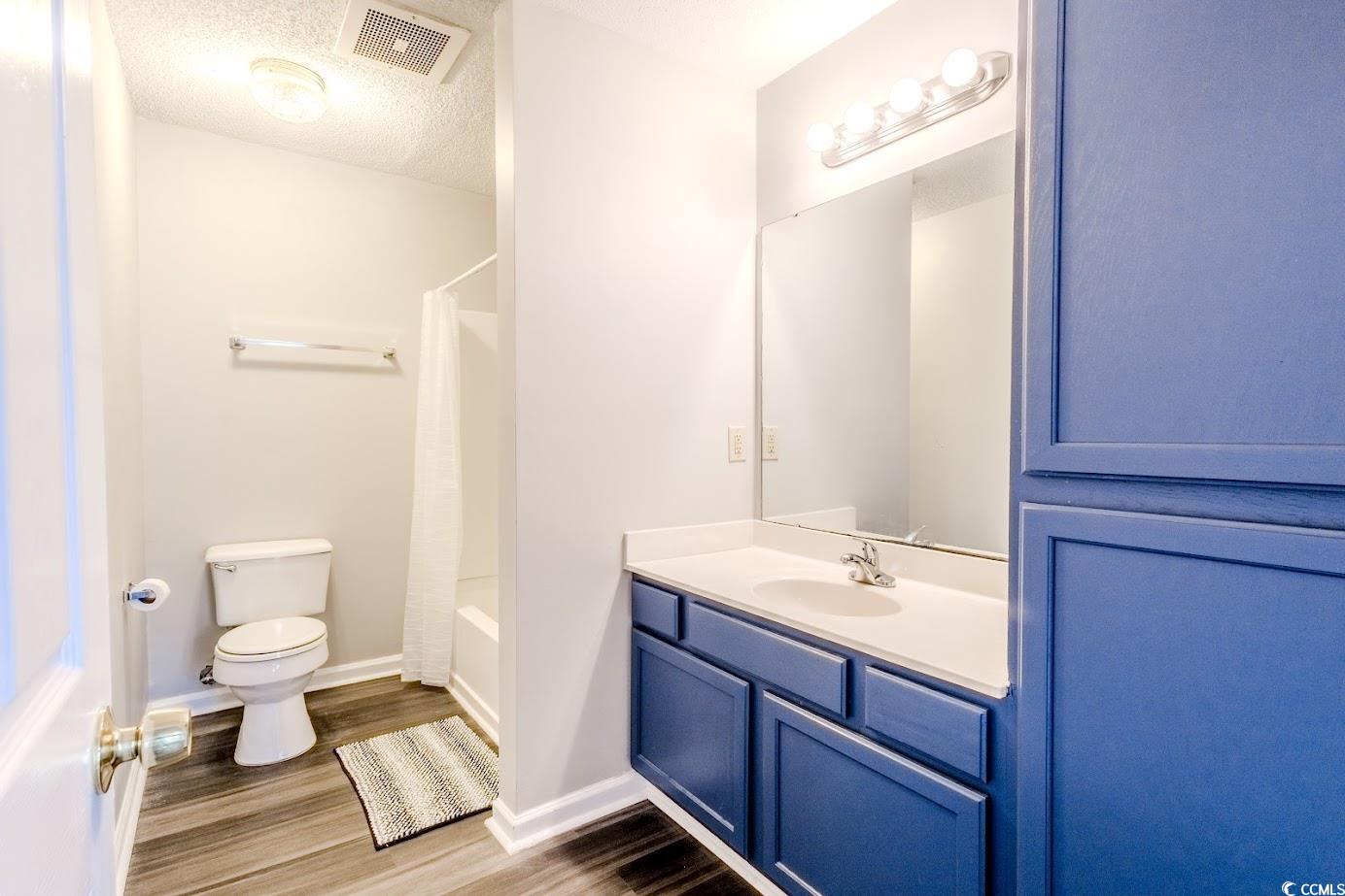 4246 Villas Drive, Unit 706 Little River, SC 29566 - Photo 15 of 20 Full bathroom with vanity, a textured ceiling, dark wood-type flooring, and shower / bath combo with shower curtain