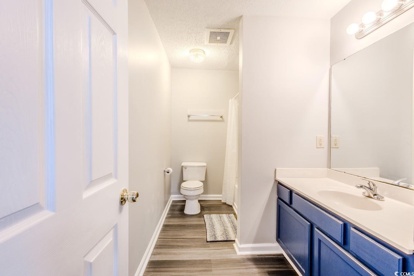 4246 Villas Drive, Unit 706 Little River, SC 29566 - Photo 16 of 20 Bathroom featuring a textured ceiling, vanity, and dark wood finished floors