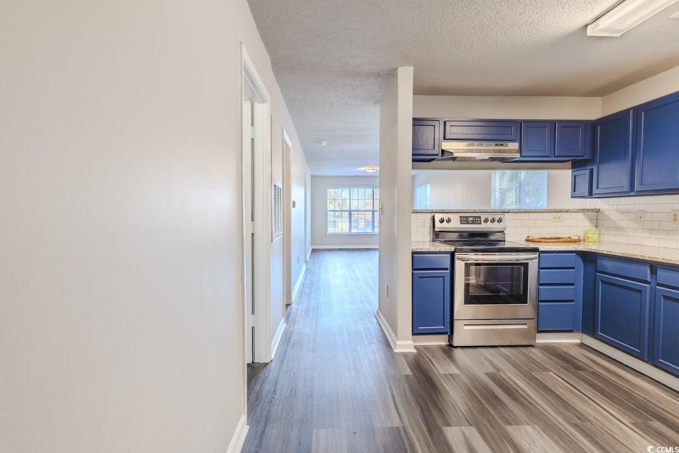 4246 Villas Drive, Unit 706 Little River, SC 29566 - Photo 3 of 20 Kitchen with dark wood-style flooring, stainless steel electric stove, blue cabinetry, a textured ceiling, and backsplash