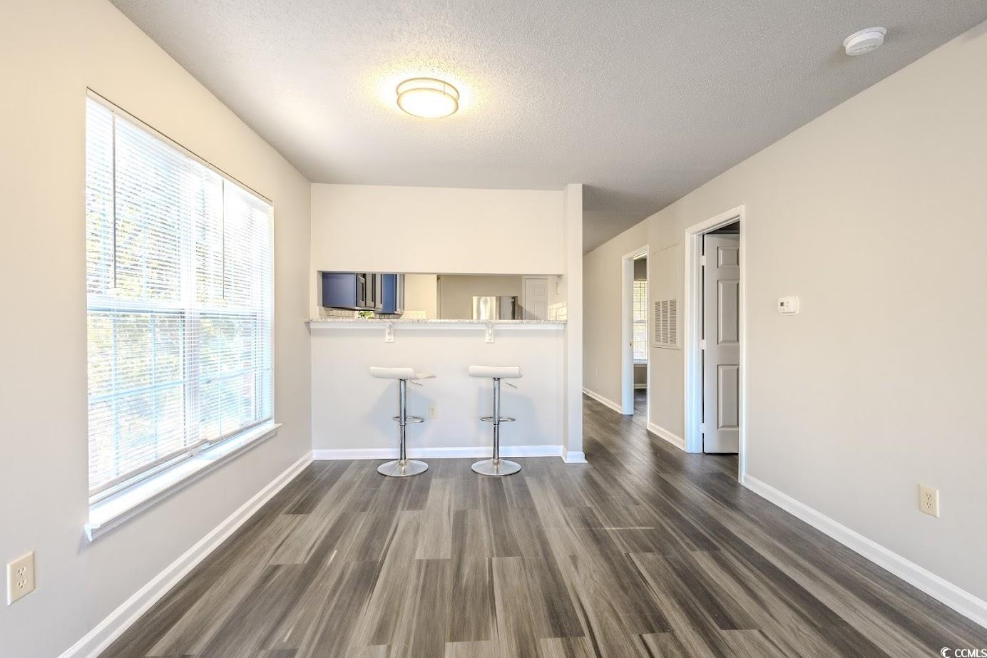 4246 Villas Drive, Unit 706 Little River, SC 29566 - Photo 10 of 20 Unfurnished living room with plenty of natural light, a textured ceiling, and dark wood-type flooring
